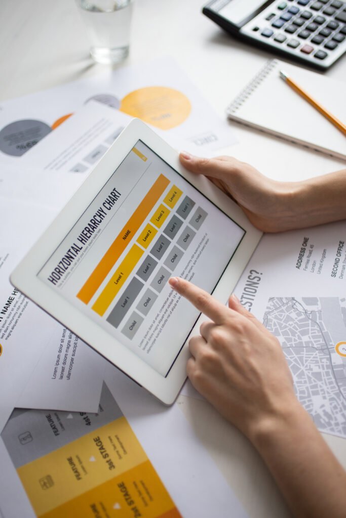 A UX designer using a tablet to review a professional information architecture services chart, ensuring organized website structure for a Cyber Aliens project.